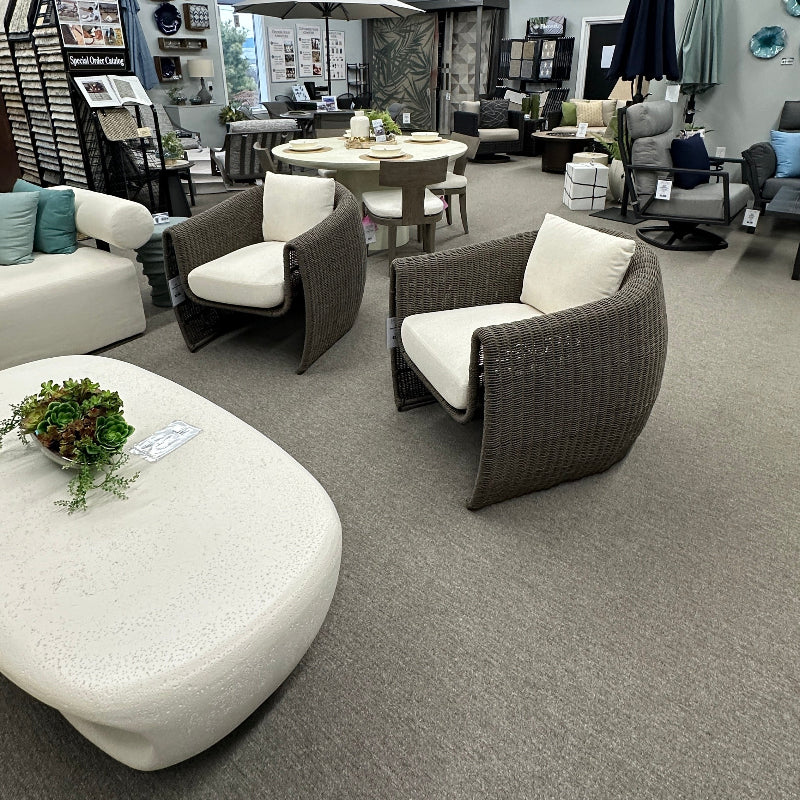 Modern living room with gray chairs, white ottoman, and decorative items.