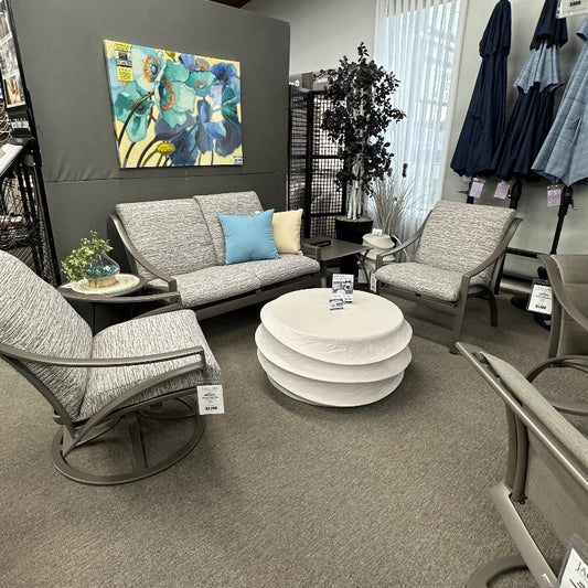 Modern living room with gray furniture, round coffee table, and abstract painting on a gray wall.
