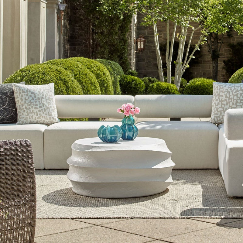 Outdoor patio setting with a white sofa, coffee table, and decorative elements.