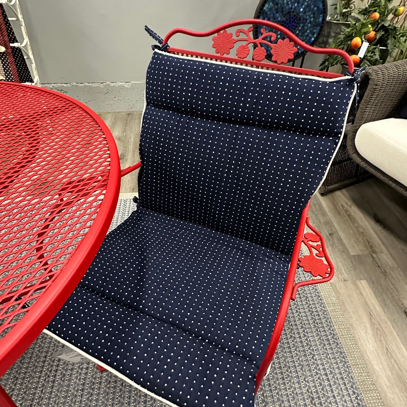 Navy cushion with white polka dots on a red metal chair in an indoor setting.