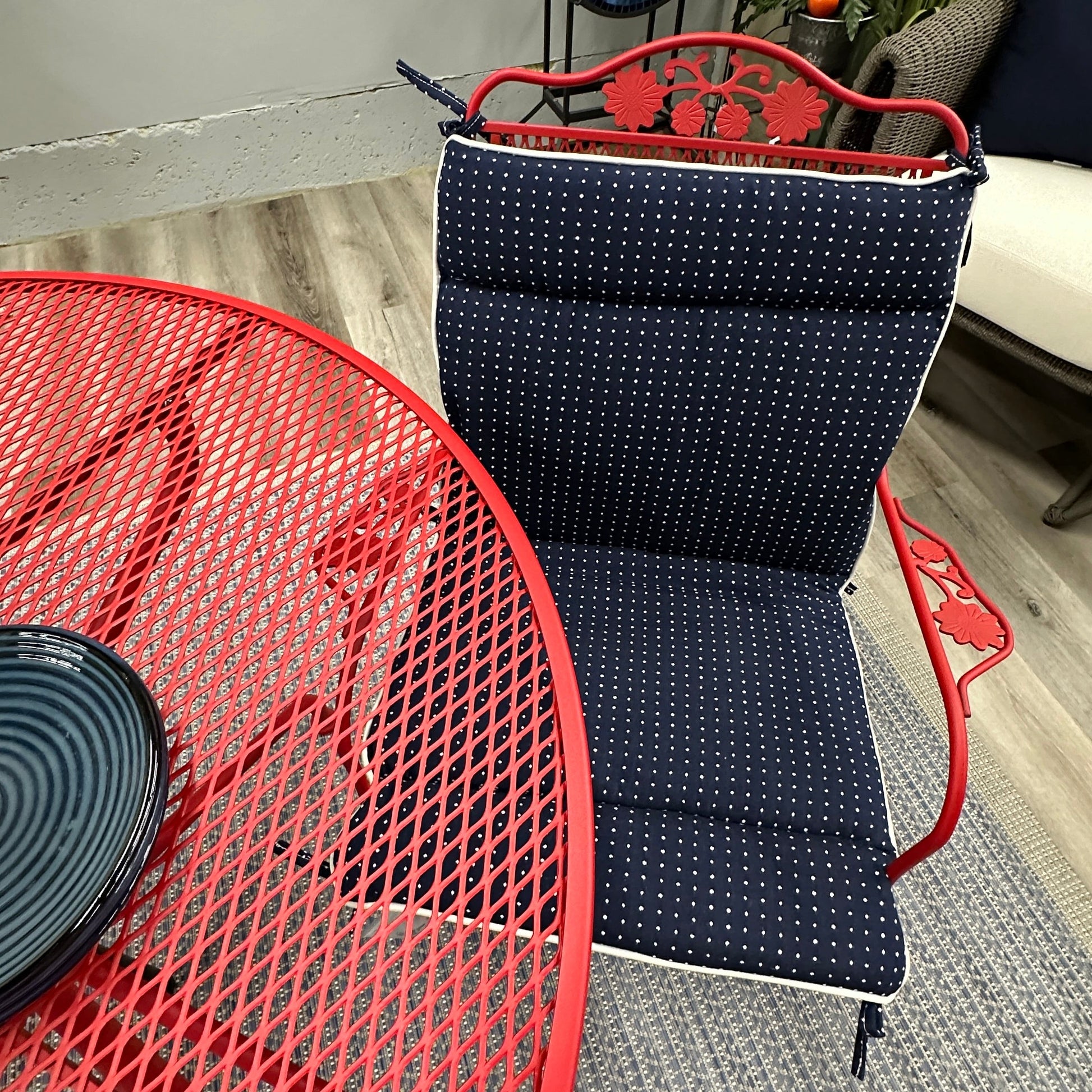 Navy chair with red frame next to a red mesh table on a gray floor.
