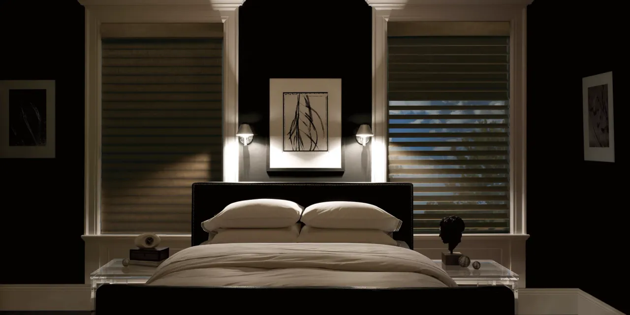Modern bedroom with a bed, nightstands, and wall art in a dimly lit room.