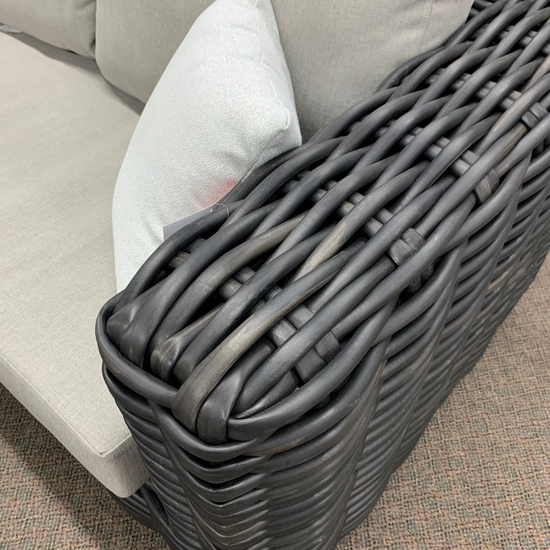 the arm of a grey resin wicker sofa