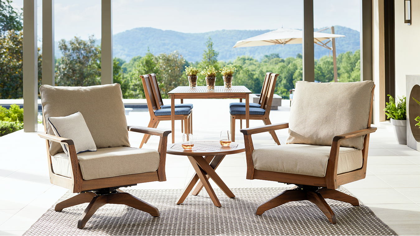 Outdoor furniture set with chairs and a table on a patio with a scenic view.