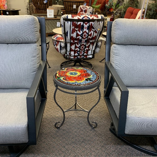 An 18 inch Zinnia Mosaic Top Side Table with a colorful floral pattern, placed between two armchairs on a carpeted floor.