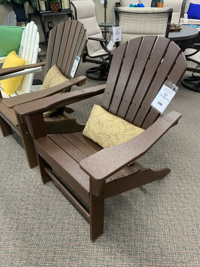 A brown POLYWOOD South Beach Adirondack chair with a cushion, displayed in an indoor setting with other chairs and patio furniture in the background.